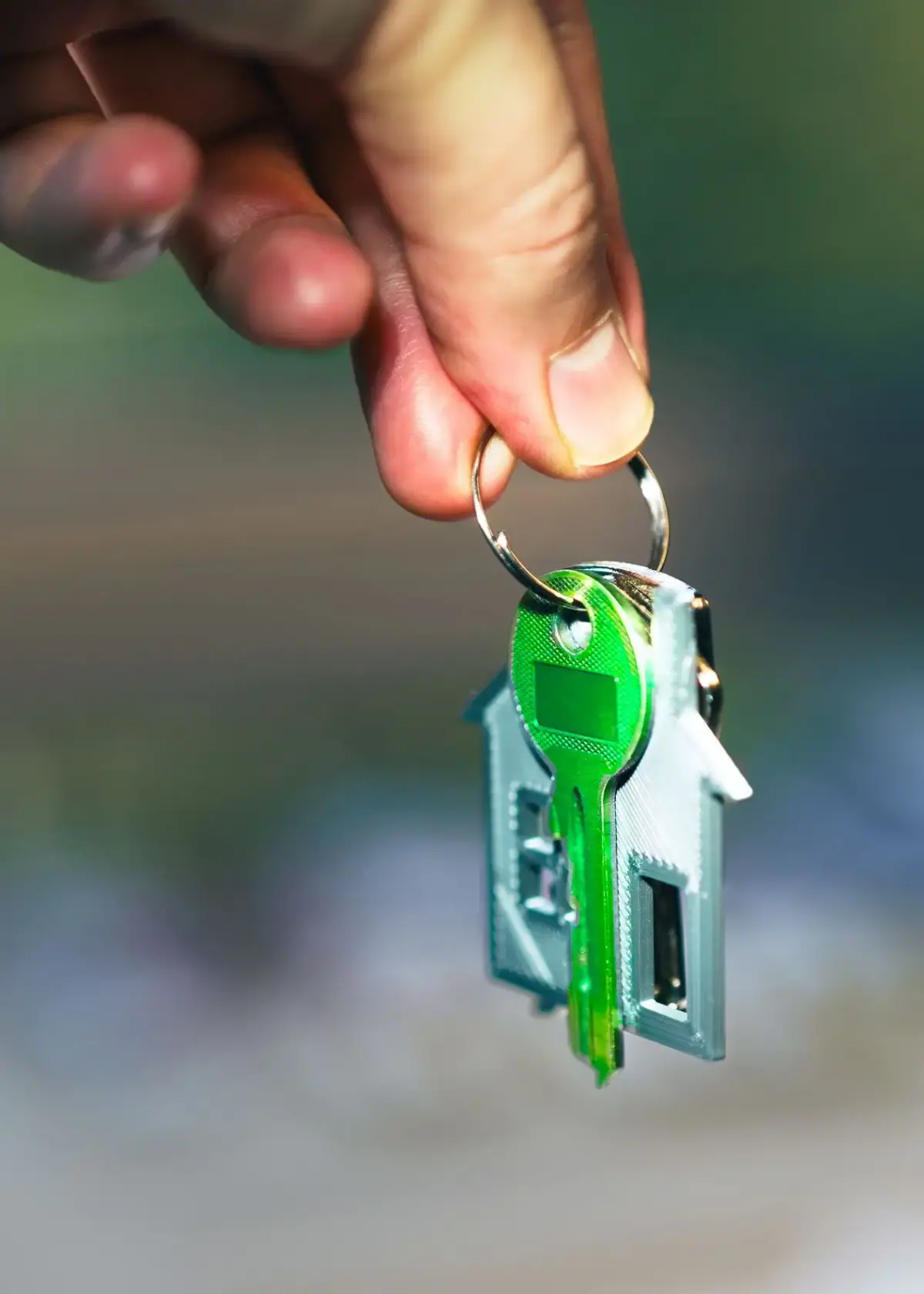 Hand holding a house key on a sunny Costa Mesa porch